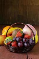 Bodegón cesta de mimbre con fruta en una mesa de madera foto