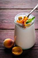Thick Greek yogurt with granola, peaches and mint photo