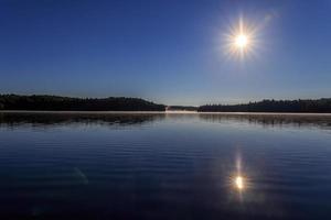 Starburst sun over calm lake photo