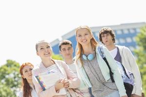 jóvenes estudiantes sonrientes de pie juntos en el campus universitario