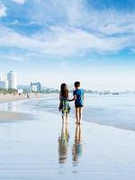 Brother sister holding hand walk on the beach photo