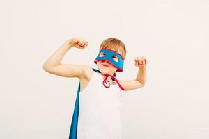 Child posing in superhero mask and cape