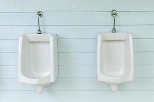 fila de urinarios blancos en el baño de hombres foto