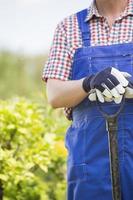Midsection of man holding spade at garden photo