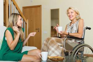 Female friend visiting disabled woman photo