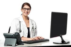 Smiling female doctor working on computer photo