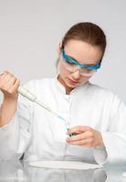 Young female scientist or tech loads sample