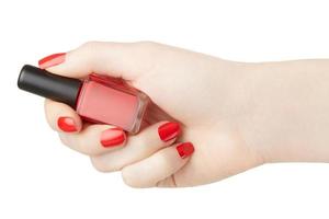 mano femenina con botella de esmalte de uñas rojo