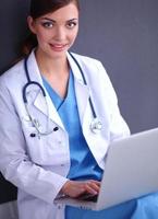 Female doctor working sitting on gray  background photo