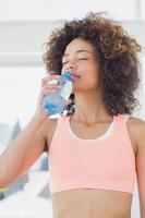 Fit female drinking water at gym photo