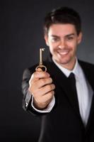 empresario sonriente sosteniendo una llave de oro