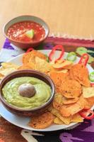 Still life with nachos, pistachio-colored guacamole, hot pepper and salsa photo