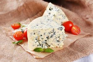 sabroso queso azul con tomate y albahaca, sobre fondo de arpillera foto