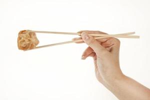 Mano sosteniendo dumpling chino wonton con palillos, aislado en blanco