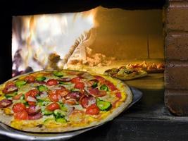pizza coming out of a wood burning oven. photo