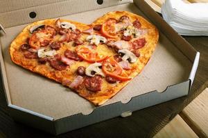 Pizza en forma de corazón sobre fondo oscuro de madera vista superior