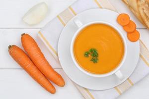 Carrot soup with fresh carrots in bowl from above photo
