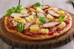 Pizza with cheese and pineapple chicken on board photo