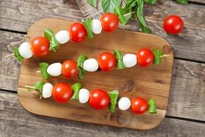 Italian traditional homemade skewers with mozzarella tomatoes and basil called photo