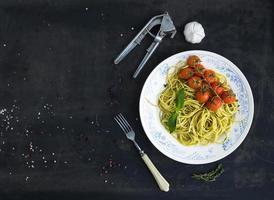 Pasta spaghetti with pesto sauce, basil, garlic, baked cherry-tomatoes