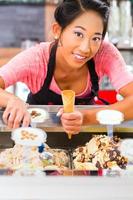 sonriente trabajadora en heladería sosteniendo un cono