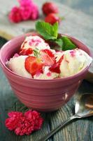 Berries and ice cream in a pink cup.