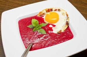 Beetroot cream soup with fried egg and bacon photo