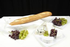 Französische tafel mit baguette, weintrauben und käse foto