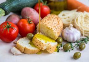 Extra virgin olive oil on white baguette and vegetables photo