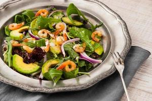Prawns and avocado salad on vintage metal plate with fork photo