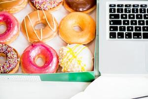 Snack from Glazed Doughnuts near Laptop on Working Desk photo
