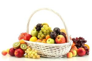 Surtido de frutas exóticas en cesta aislado en blanco foto