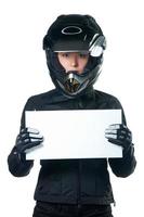 Woman in motorcycle clothing holding a white board.