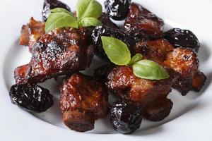 Pork ribs stewed with prunes and basil close-up. photo