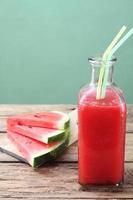 watermelon smoothie in glass bottle on rustic table photo