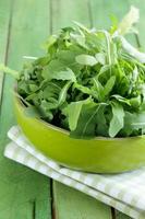 bowl of green salad with arugula on wooden table photo
