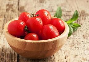 tomates en un recipiente en la mesa de madera, enfoque selectivo