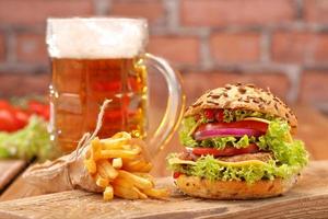 Grilled hamburger with fries and beer on brick wall background photo
