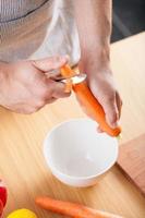 hombre pelando zanahoria en la cocina foto