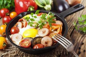 Fried eggs with vegetables and sausage photo