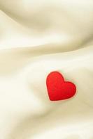 Corazón decorativo de madera roja sobre fondo blanco de seda. foto