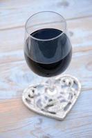 glass of red wine with rose and heart decoration photo