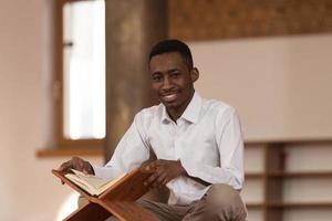 Hombre musulmán africano leyendo sagrado libro islámico Corán