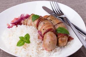 grilled bavarian sausages with rice and mint on white dish