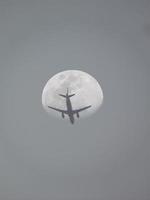 Avión de pasajeros volando contra la luna, vista de ángulo bajo foto