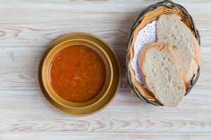 Bowl of minestrone soup with bread on wood table