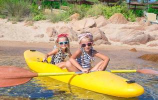 Little adorable girls enjoying kayaking on yellow kayak photo