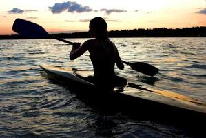 silueta de mujer kayakista en medio de un lago foto