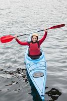 mujer feliz en un kayak animando a la cámara
