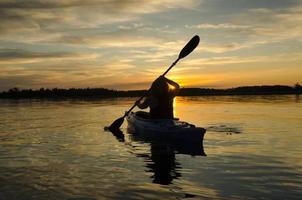 mujer kayaks al atardecer foto